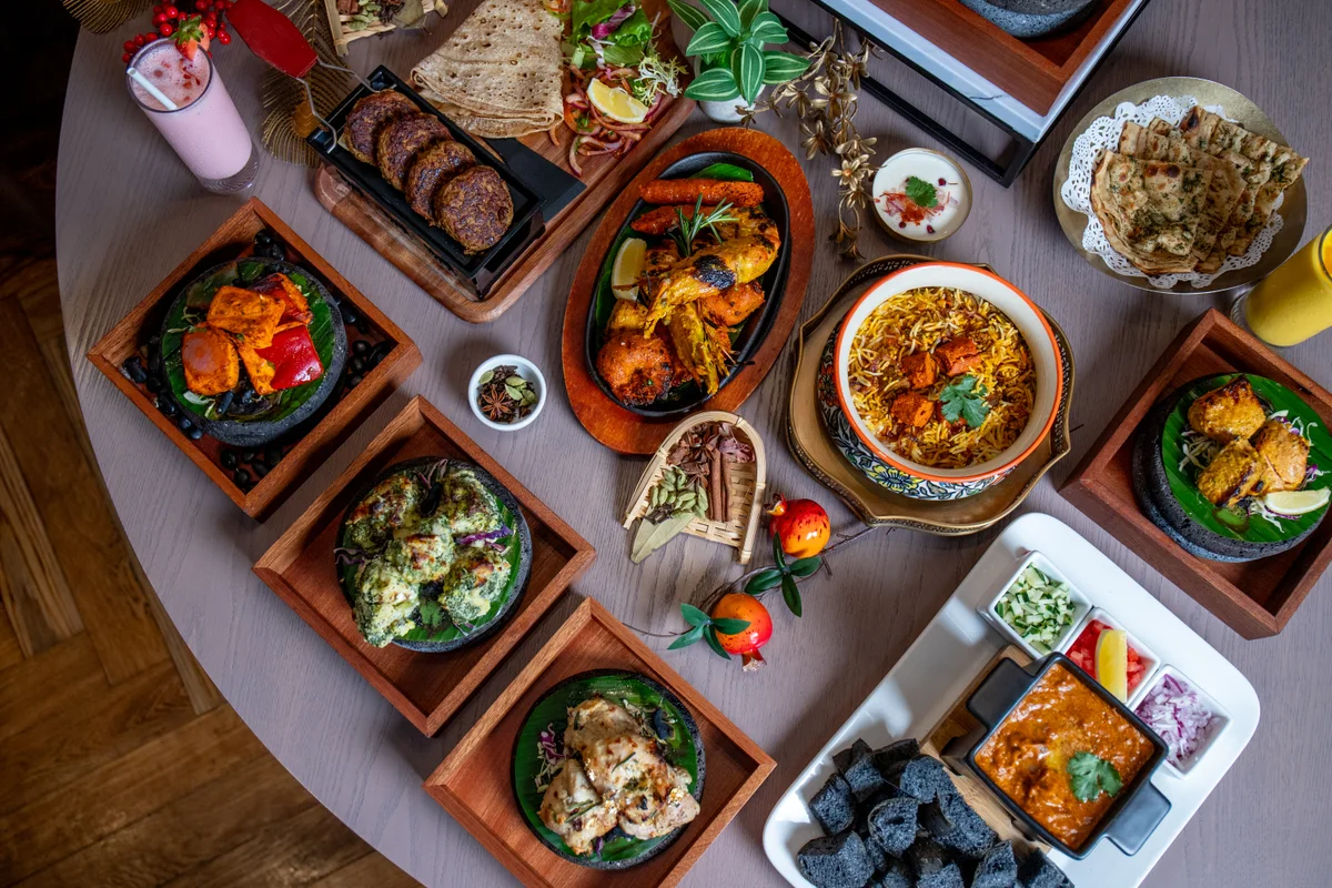 An overhead table of tandoor dishes, curries, biryani and drinks