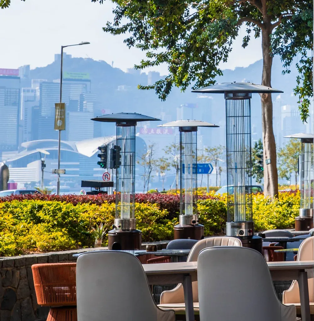 The view from Tagline’s patio: outdoor heaters and trees, with Victoria Harbour and the Hong Kong Island skyline beyond