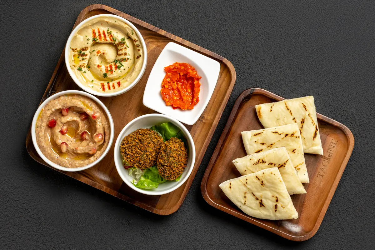 A mezze platter with hummus, dips and grilled pita on wooden boards