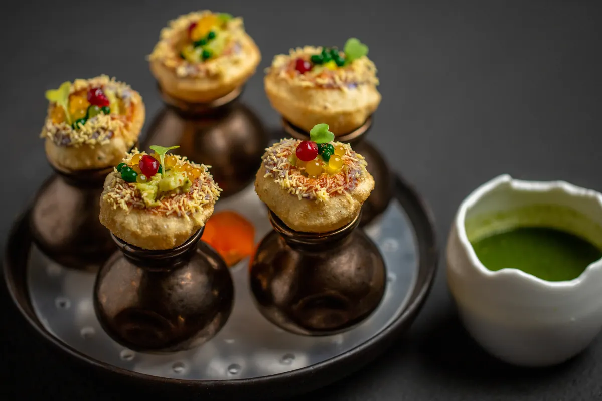 Pani puri on small bronze pots, with a pot of green chutney