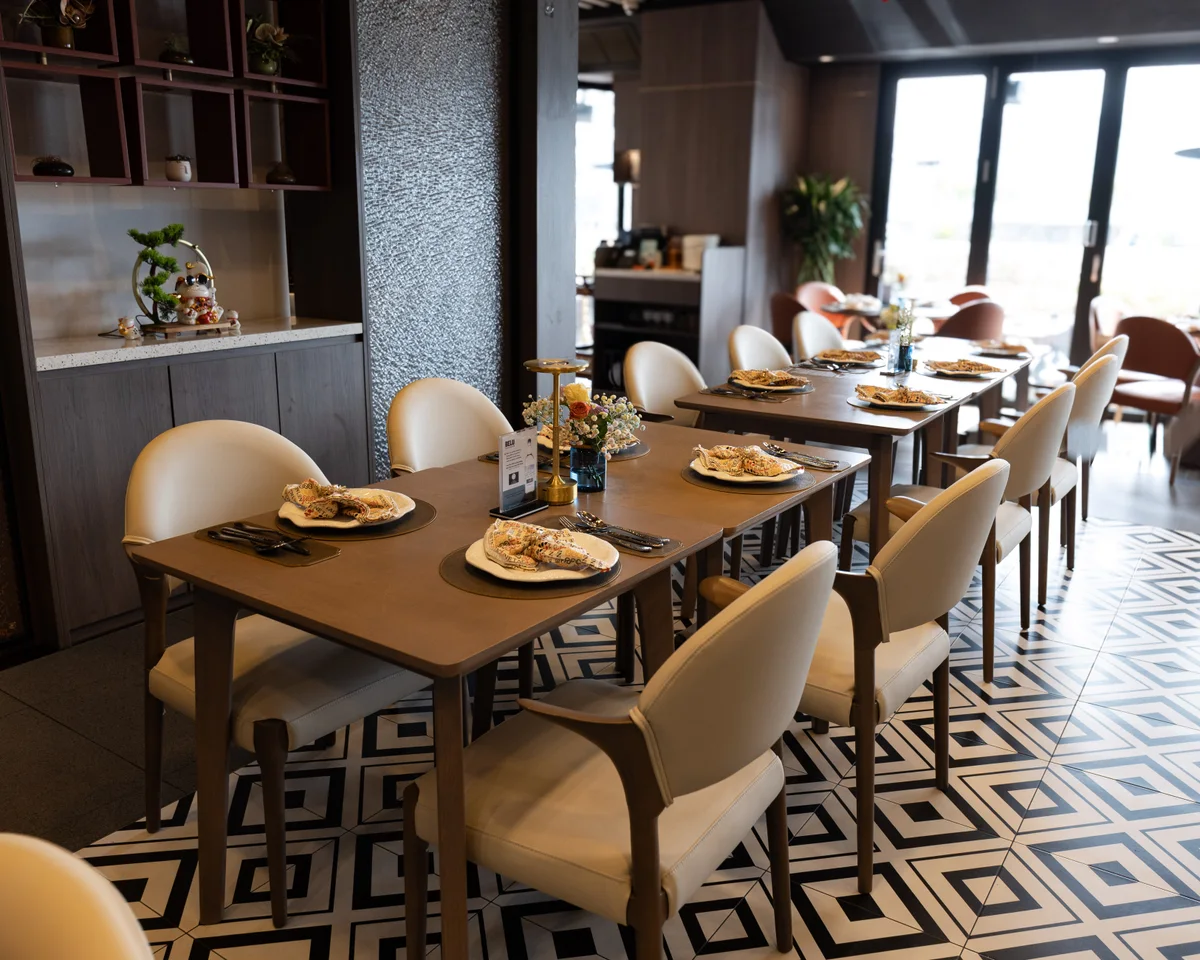 Long tables laid for a group in Tagline’s dining room, with cream chairs and a patterned floor