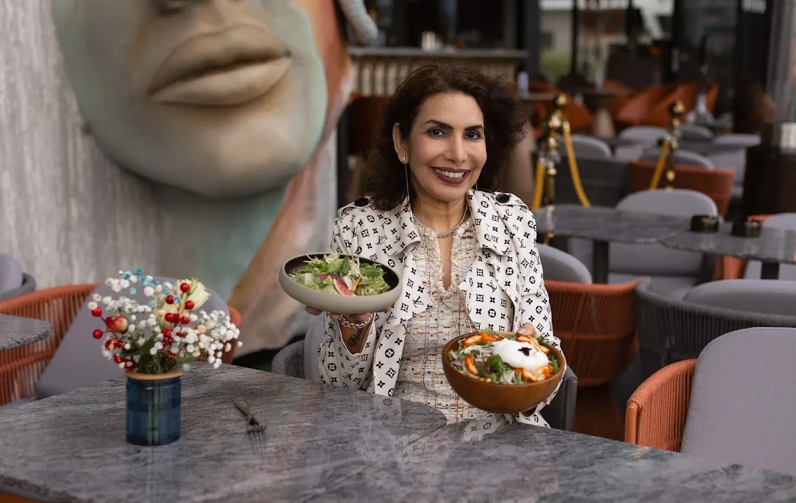 Kiran Sukhani presenting dishes at a table on Tagline’s patio